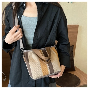 Detail of a large striped canvas tote bag with woven handles and an adjustable shoulder strap