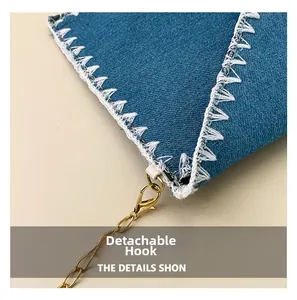 Détail en denim bleu avec coutures triangulaires blanches et crochet doré amovible