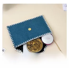 Capacité interne du sac en denim bleu montrant téléphone et cosmétiques avec chaîne dorée