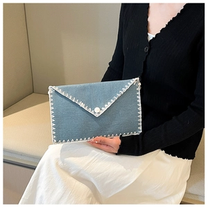 Gros plan sur l'enveloppe en denim bleu clair avec dentelle blanche et bouton perle
