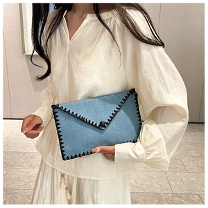 Détail de la pochette en jean avec surpiqûres zigzag, bouton et bandoulière chaîne