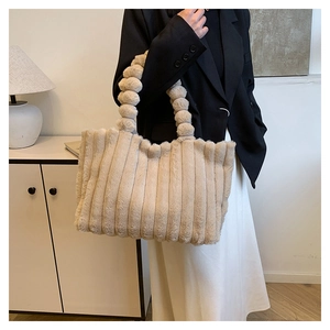 Detail of plush beige tote bag featuring fuzzy vertical stripes and bubble handle design