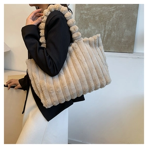 Detailed view of beige plush tote bag featuring vertical stripes and pom-pom handle strap