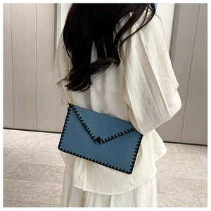 Pochette en denim bleu avec surpiqûres zigzag noires et chaîne dorée fine