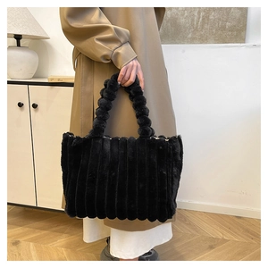 Detail of black faux fur handbag with vertical stripes and fluffy pompom handle