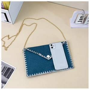 Détail du sac enveloppe en toile bleue avec chaîne métallique et téléphone de référence