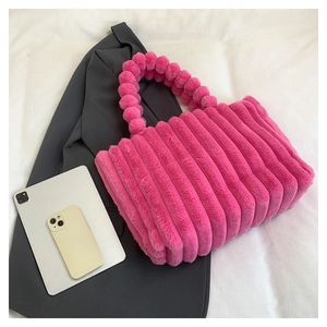 Detail of rose pink plush handbag with 3D striped texture and pom-pom bead handle
