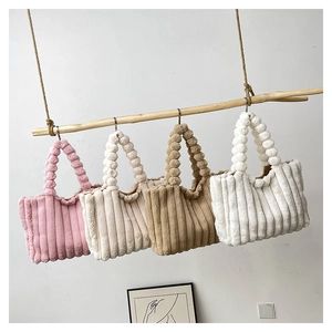 Detailed view of four colorful plush handbags hanging on a wooden beam with bubble handles