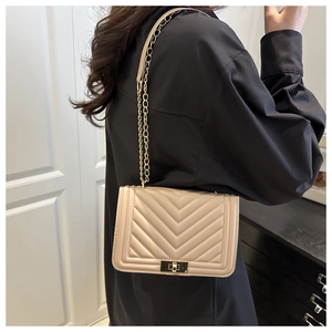 Détail du sac beige matelassé en V avec chaîne dorée et fermoir rotatif carré chic