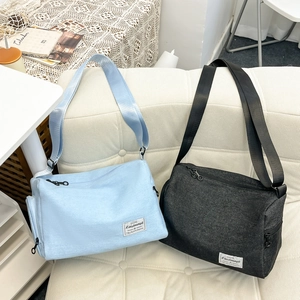 Minimalist Harajuku style large messenger bags in light blue and charcoal black on a sofa