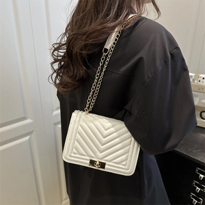Sac bandoulière blanc élégant à matelassage en V et chaîne dorée porté par un mannequin