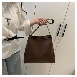 Detail view of large brown tote bag with adjustable shoulder strap and matte leather finish