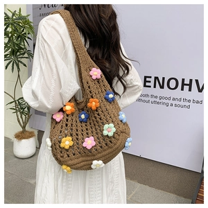Borsa a spalla in maglia marrone con fiori 3D colorati indossata da modella in bianco