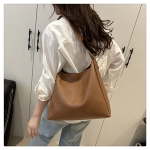 Side view of a large caramel brown tote bag worn over the shoulder with casual denim outfit