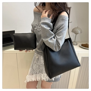 Close-up of minimalist black tote and matching pouch set in a chic lifestyle setting
