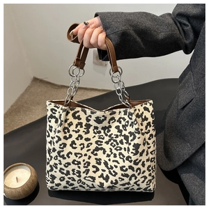 Détail d'un sac cabas léopard avec poignées en cuir marron et chaînes en métal argenté