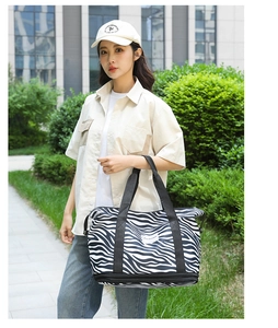 Detail of zebra pattern travel tote showing black wide handles and waterproof fabric texture