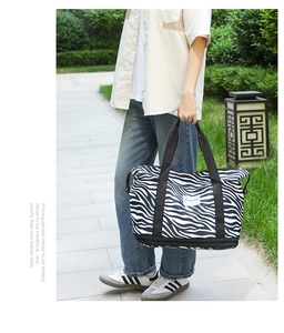 Detail of zebra print travel tote featuring double-layered bottom with zip compartment