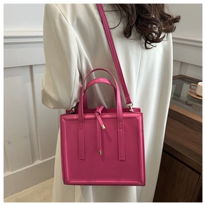 Vertical hot pink leather crossbody bag shown on model highlighting size and elegant shape