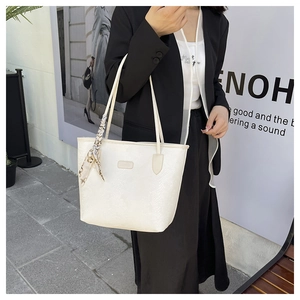 Dettaglio della borsa tote crema in pelle goffrata con sciarpa decorativa in seta sul manico