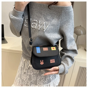 Vue détaillée du sac besace noir mat avec écussons colorés porté par un mannequin