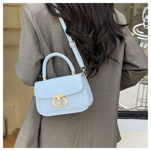 Detail of light blue leather handbag with golden metal buckle and adjustable strap