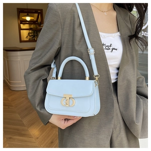 Detail of light blue crossbody bag featuring a golden metal T-bar twist lock closure