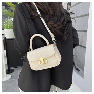 Close-up of white leather crossbody bag featuring iconic gold T-shaped buckle detail