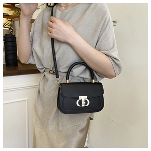 Detailed close-up of a small black leather crossbody bag with a gold metal twist lock