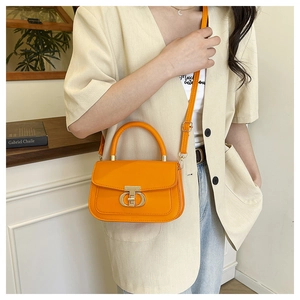 Detail of orange handbag with gold CD lock buckle on light beige blazer outfit