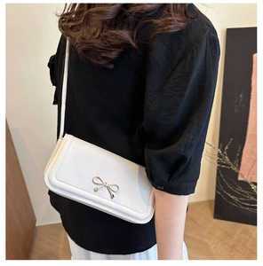 Detail of white glossy leather bag with a distinctive golden bow metal lock closure