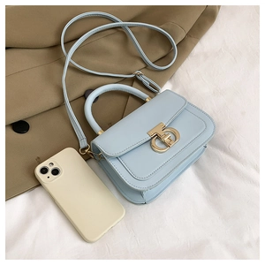 Detailed top view of light blue crossbody bag with gold T-clasp and leather texture