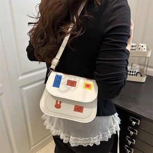 Sac à bandoulière blanc chic avec imprimés lapins ludiques porté dans un cadre décontracté