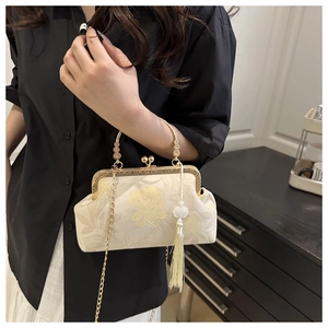 Détail de la broderie florale beige, de l'anse dorée et du gland en soie du sac vintage