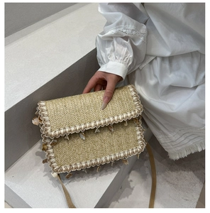 Detail of straw woven bag with lace trim and seashell charms on a leather strap