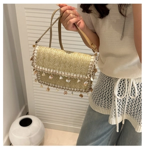Detail of woven straw shoulder bag with lace edges and decorative seashells