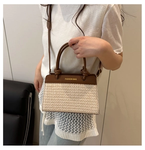 Detail of a chic straw patchwork tote bag with brown leather and gold lettering