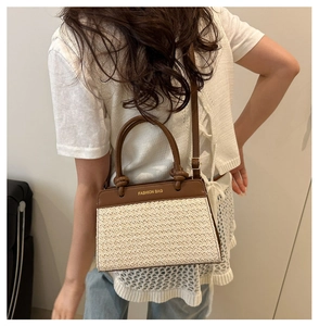 Detail of woven straw crossbody bag with brown leather straps and adjustable shoulder belt