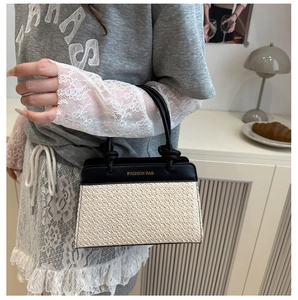 Detail of a chic two-tone handbag featuring a woven texture and golden fashion logo