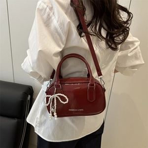 Sac polochon en cuir verni rouge foncé avec nœud en perles et bandoulière chic