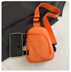 Détail du sac bandoulière orange en nylon avec bandoulière réglable et smartphone pour taille