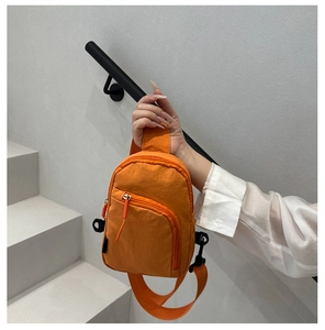 Détail d'un sac de poitrine orange vif en nylon avec fermetures éclair et bandoulière