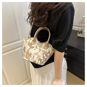 Détail de la broderie florale et de l'anse en cuir sur un sac bandoulière vintage