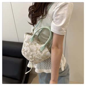 Détail d'un sac bandoulière brodé de fleurs vert menthe avec poignées en cuir