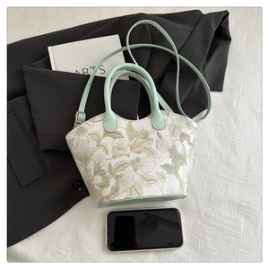 Gros plan de la broderie florale sur sac à main vert clair avec accessoires de taille