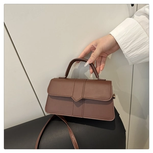 Detailed view of a brown vintage leather handbag with flap cover and cylindrical handle