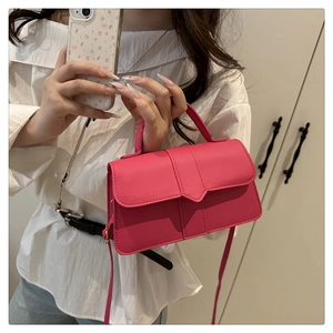 Detailed view of magenta crossbody bag with V-shaped flap closure and smooth leather finish