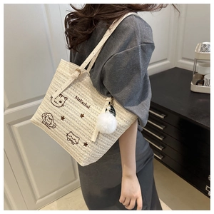 Détail d'un sac cabas tissé avec broderie chat et pendentif pompon blanc doux