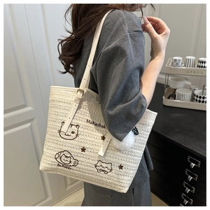 Détail d'un sac cabas tissé avec broderie chat et pendentif pompon blanc soyeux