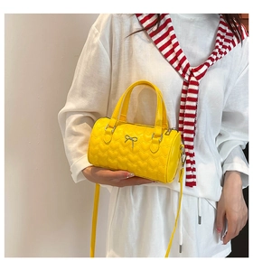 Détail du sac barillet jaune avec broderie cœur, nœud et bandoulière réglable